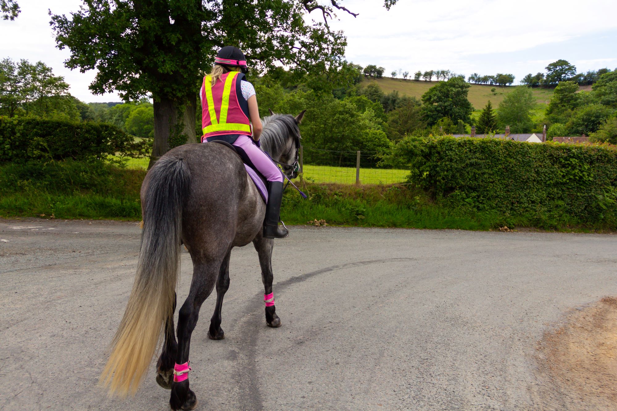 Horse rider wearing reflective safety wear on the road in the countryside