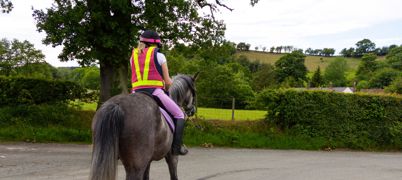 Horse rider wearing reflective safety wear on the road in the countryside