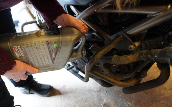 Someone adding oil to a motorbike