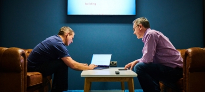 Two men sitting at a table with a laptop at Sandstone Technology