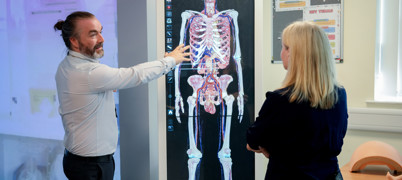 Man points at diagram of human body and skeleton 