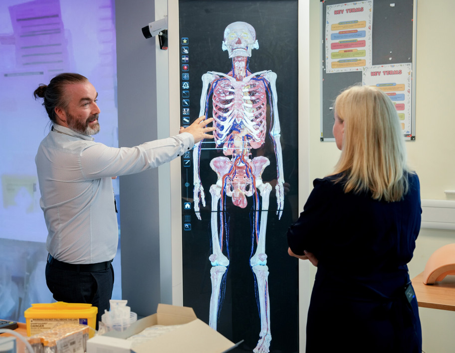 Man points at diagram of human body and skeleton 