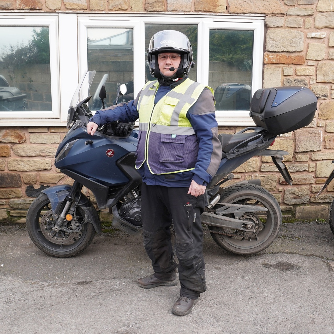 A man stood next to a parked motorbike, wearing full safety gear for riding