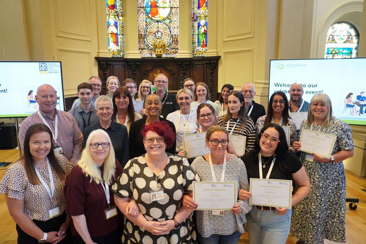 A group stood together in three rows with some holding certificates in a church backdrop