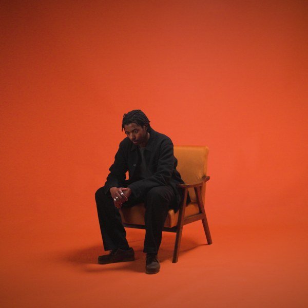 Nigel Ngwenya sat on a chair with a red background