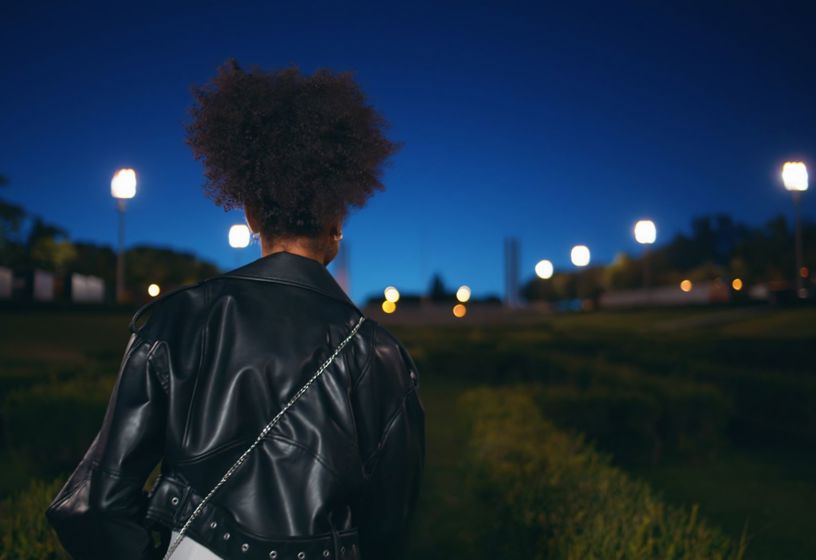 A young woman walking through a park at night