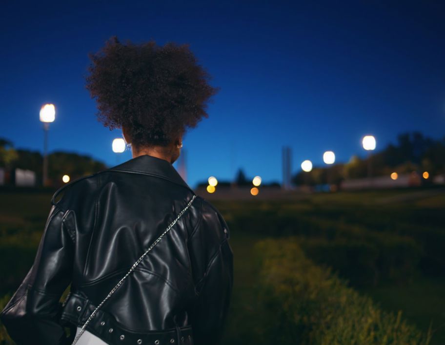 A young woman walking through a park at night
