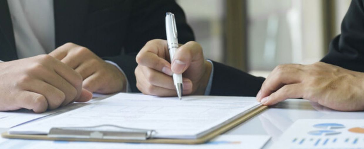 Two men signing papers on a clipboard