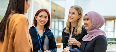 Three young women smile at one woman