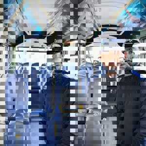 Police Community Support Officer in uniform smiling on bus