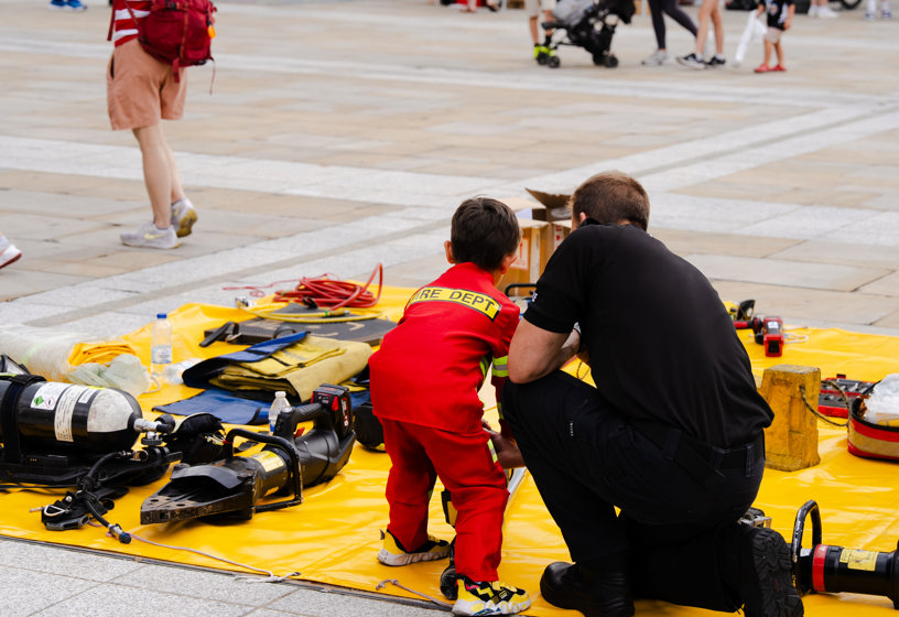 A fire fighter and young child looking at fire service equipment