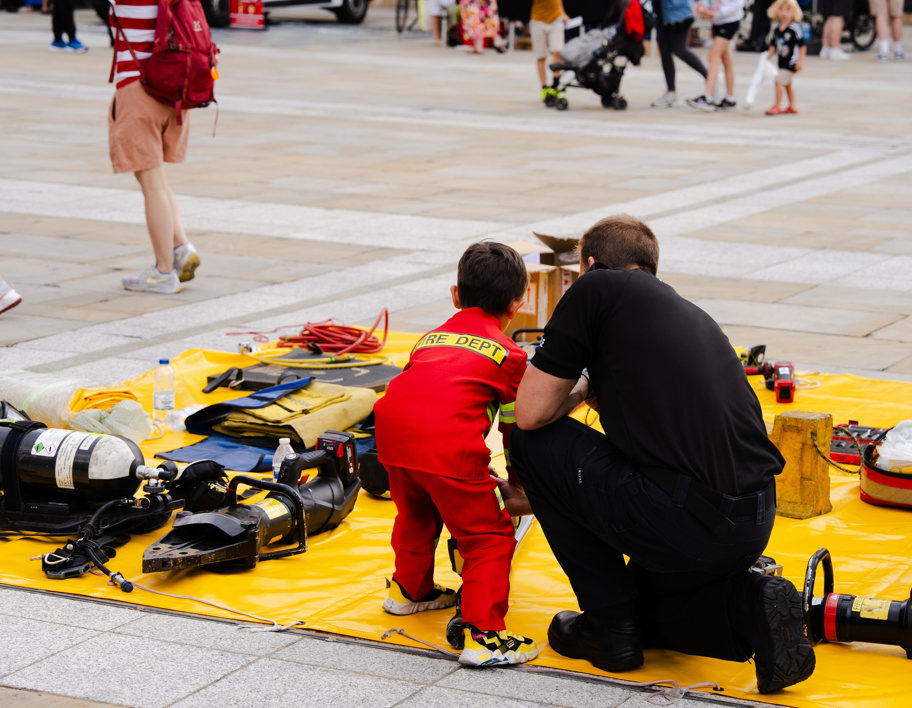 A fire fighter and young child looking at fire service equipment