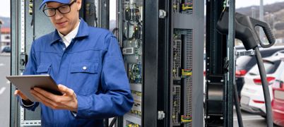 Man in blue cap and overalls writes up report beside engineering equipment