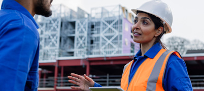 Construction engineers wearing hard hats holding clipboards