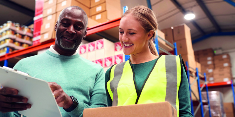 Two people in a warehouse reading a clipboard
