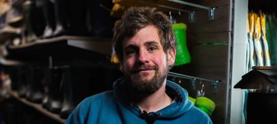 A man sat in a hardware shop, smiling