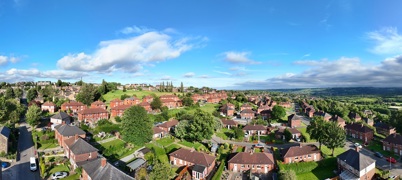 Aerial vista view of homes with open countryside in the distance and blue sky with some clouds