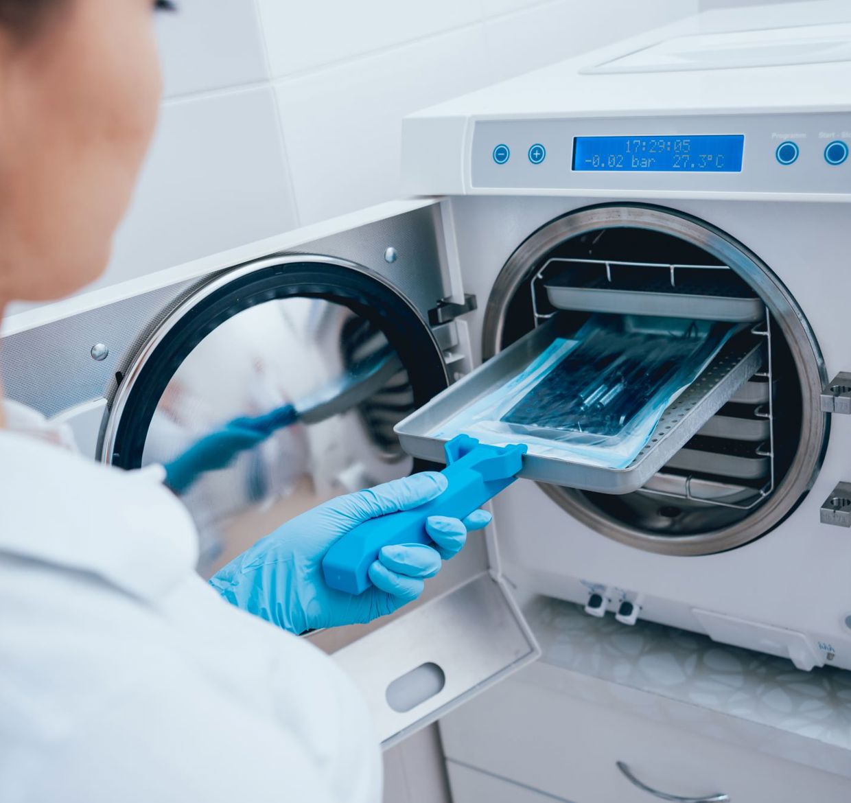 A woman sterilizing medical instruments in an autoclave