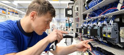 An Electrician Working On Electrical Components In A Factory Setting