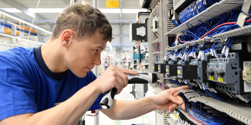 An Electrician Working On Electrical Components In A Factory Setting
