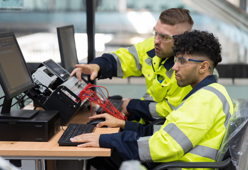 Technicians in high vis clothing working at a desk