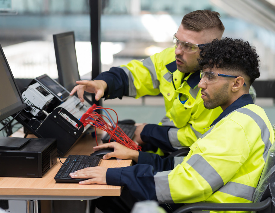 Technicians in high vis clothing working at a desk