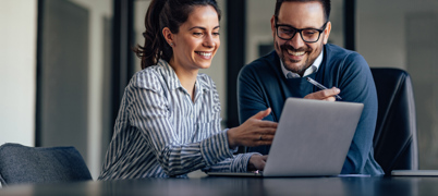 Colleagues working and smiling together at laptop