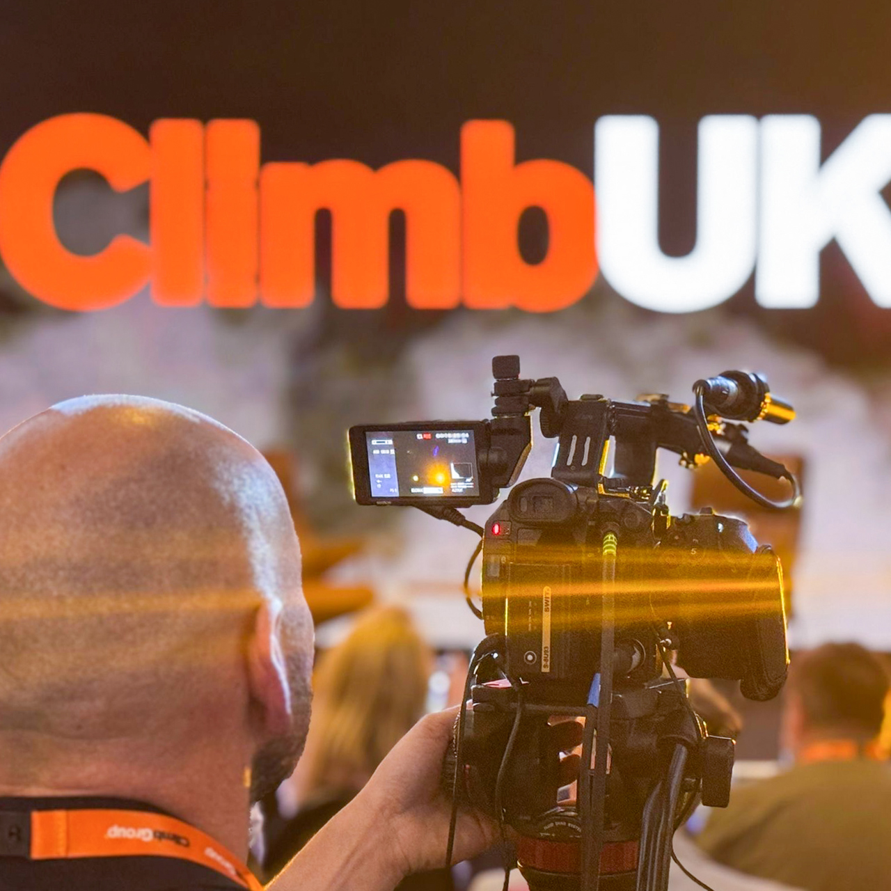 Image of a man with a camera with ClimbUK logo on the screen in front of him