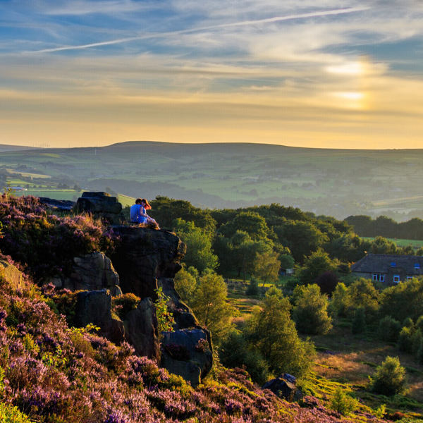 Man and woman on moorland at sunset