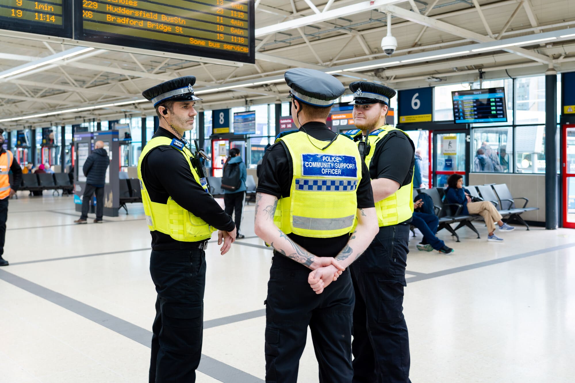 Three police officers speaking together and smiling in Leeds bus station