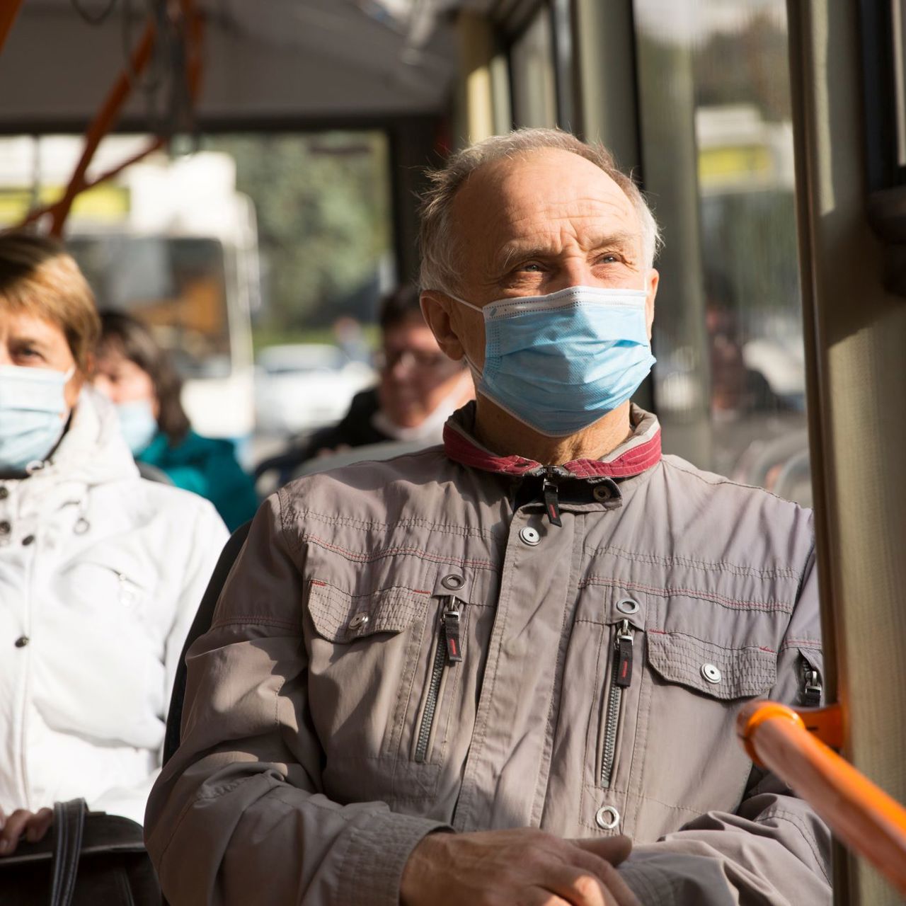 Senior man wearing a face mask whilst sitting on a bus