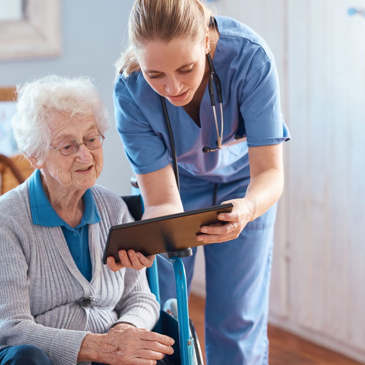 A nurse and an elderly patient looking at medical results on a tablet
