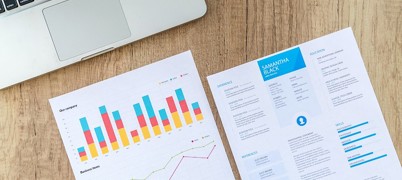 Pieces of paper with charts and a laptop