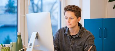Woman makes notes while looking at desktop