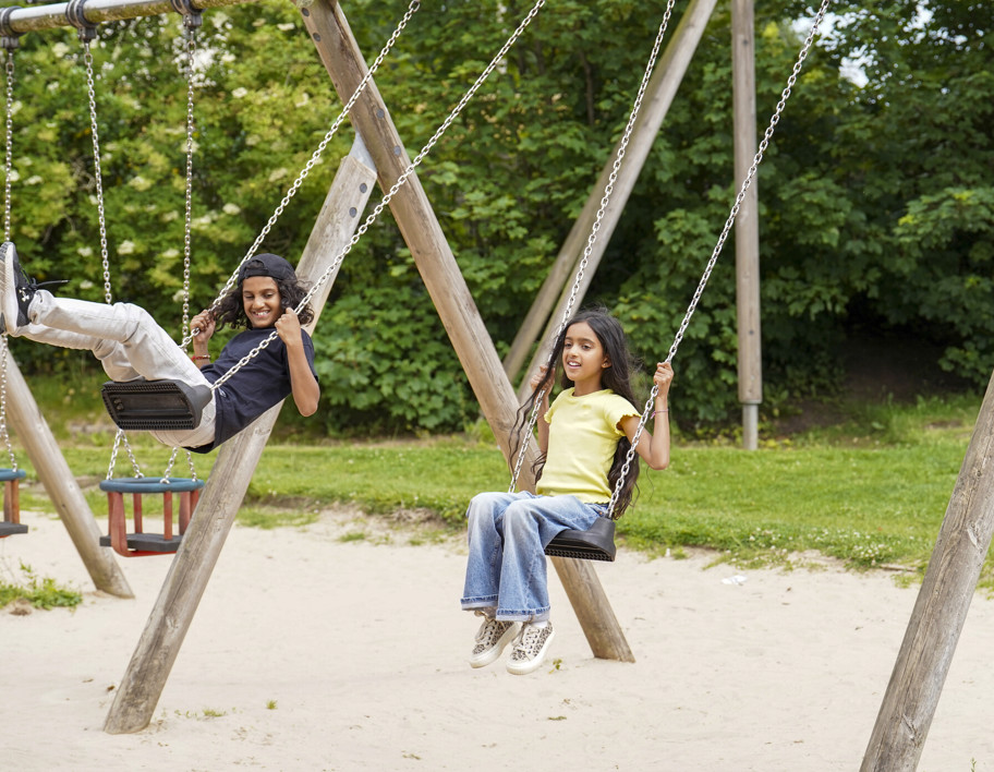 Two children on swings in a park