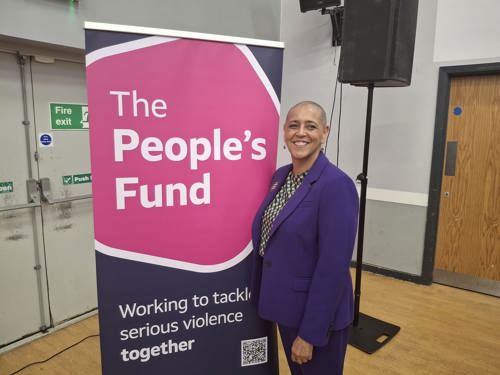 Deputy Mayor Alison Lowe standing in front of a roll-up pink and blue banner with the 'People's Fund, working to tackle serious violence together' written on it