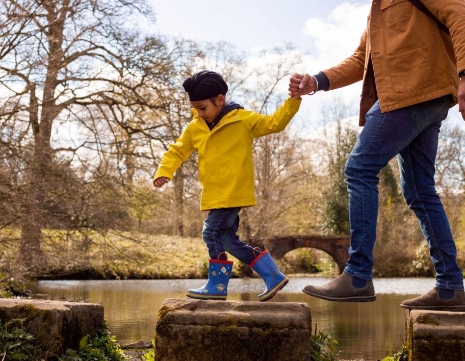A young Sikh boy and his parent walking across stepping stones