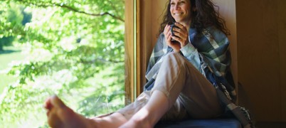 Woman sat with a mug on a windowsill, smiling