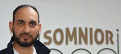 A man pictured in front of a Somnior Bed sign