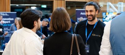 Man with black beard and tied up hair smiles at two people