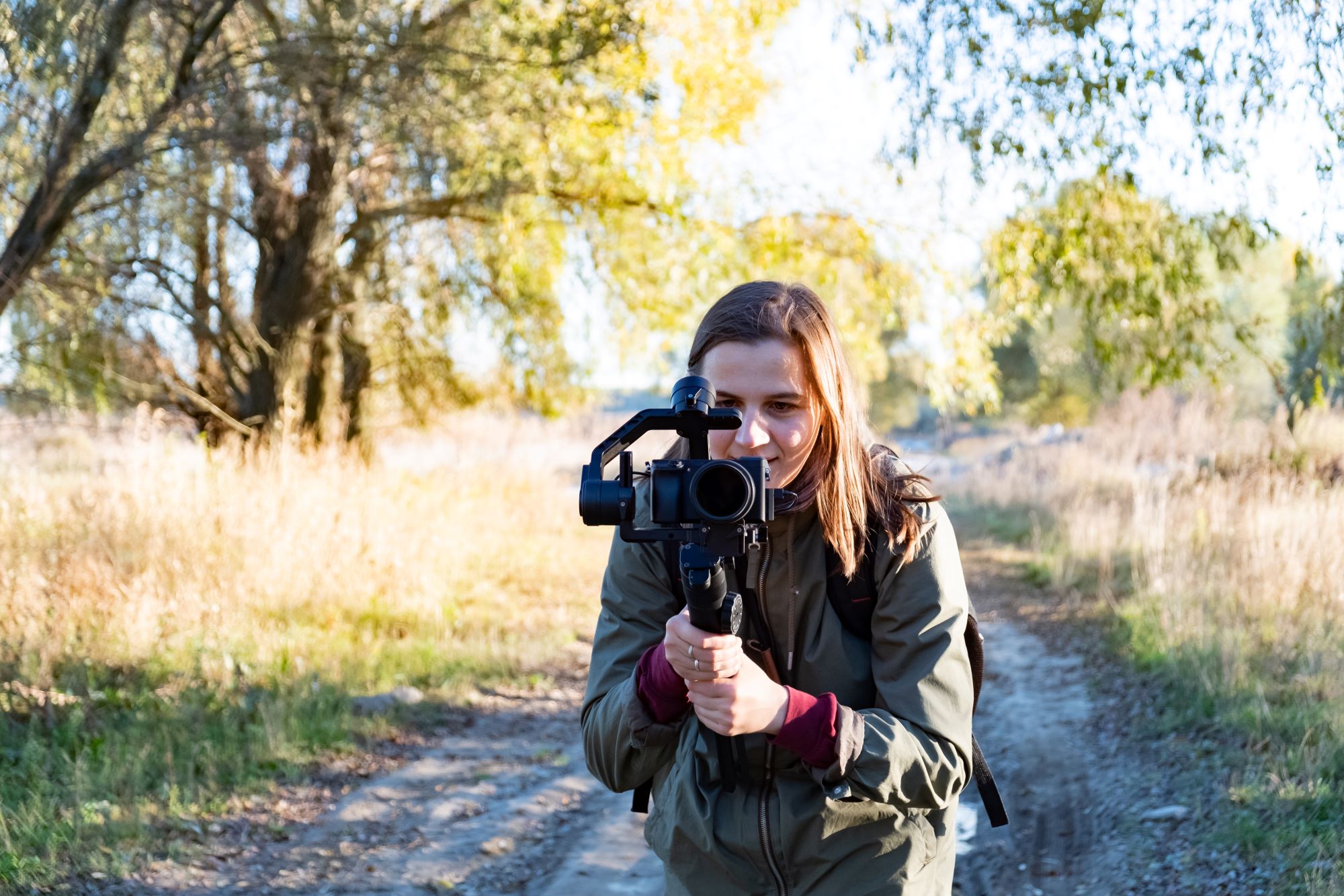 Female Videographer Holding A Gimbal With Camera, Filming Outdoors On A Sunny Afternoon