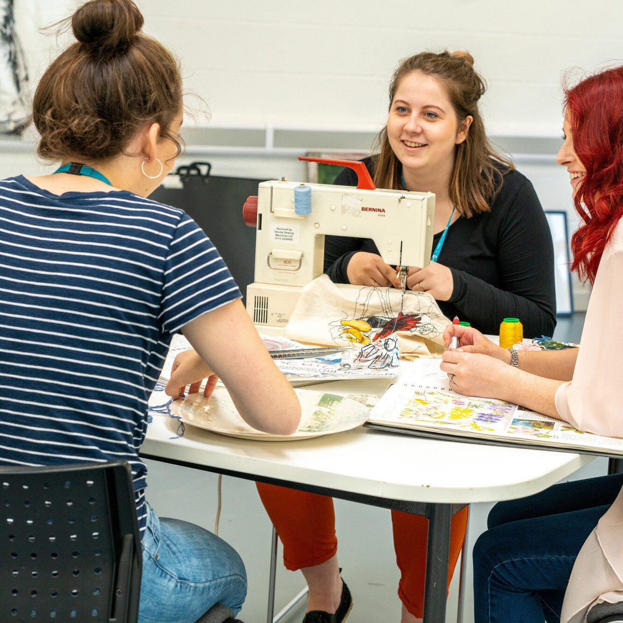 Students sewing together at table 