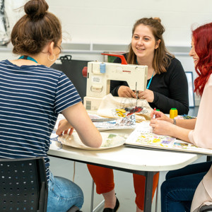 Students sewing together at table 
