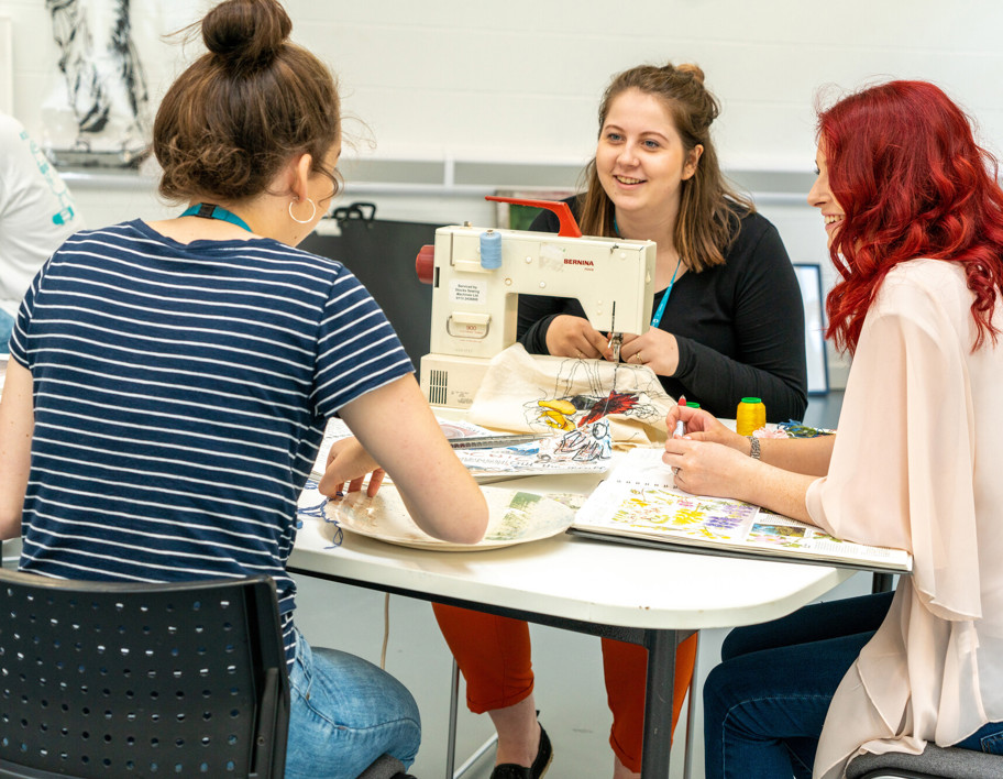 Students sewing together at table 