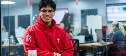 A man sat in a red jumper at a table, smiling