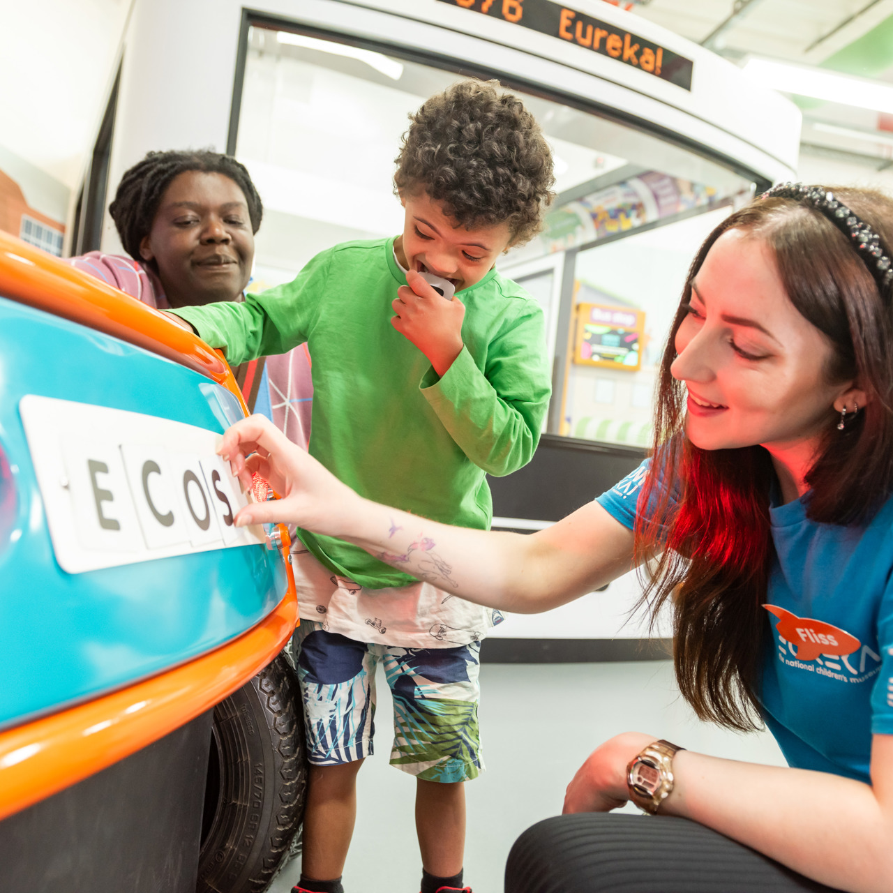 Eureka! staff displaying the Eco-Street exhibition to a child and an adult
