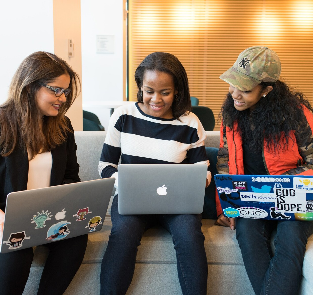 Group of students sitting together with laptops, smiling