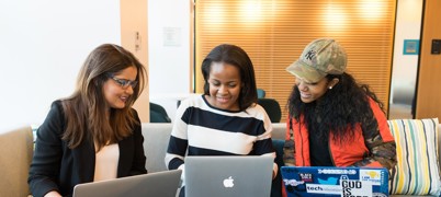 Group of students sitting together with laptops, smiling